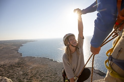 Man and young woman near top of rock climb