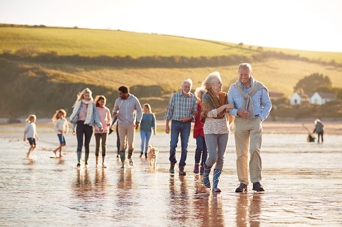 Mehrere-Generationen-Familie mit Hund beim Strandspaziergang im Winter