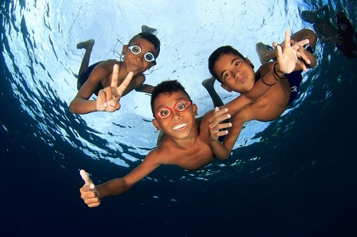 Drei Kinder tauchen und lächeln in die Kamera